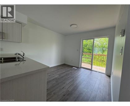 A kitchen with a sink and a window overlooking a green area.