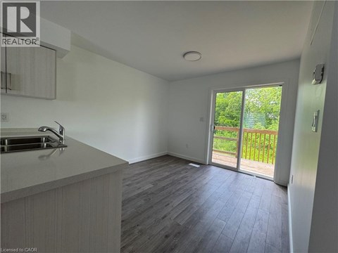 A kitchen with a sink and a window overlooking a green area.