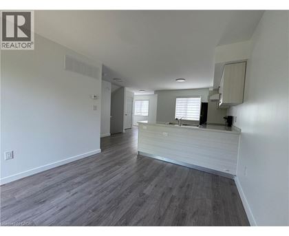 A spacious room with wooden flooring and white walls.
