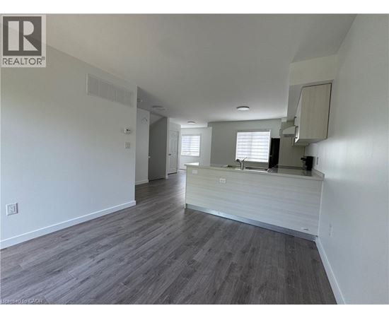 A spacious room with wooden flooring and white walls.