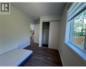 A bedroom with a bed, a window, and a door leading to another room.