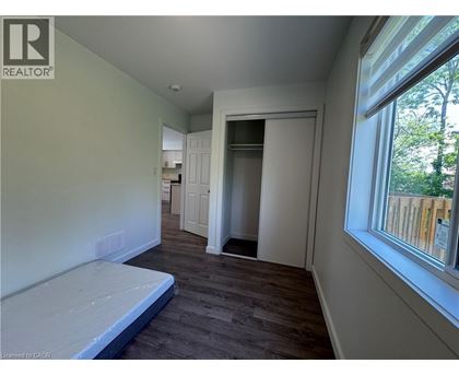 A bedroom with a bed, a window, and a door leading to another room.