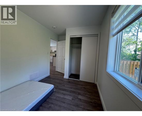 A bedroom with a bed, a window, and a door leading to another room.