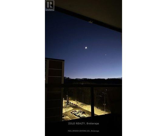 A view from a window at night showing a parking lot and a clear sky.