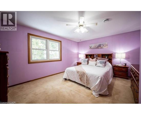 A bedroom with a bed, dresser, and window.