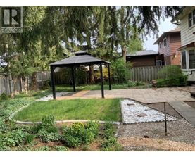 A gazebo is in the middle of a garden with a gravel area in front of it.