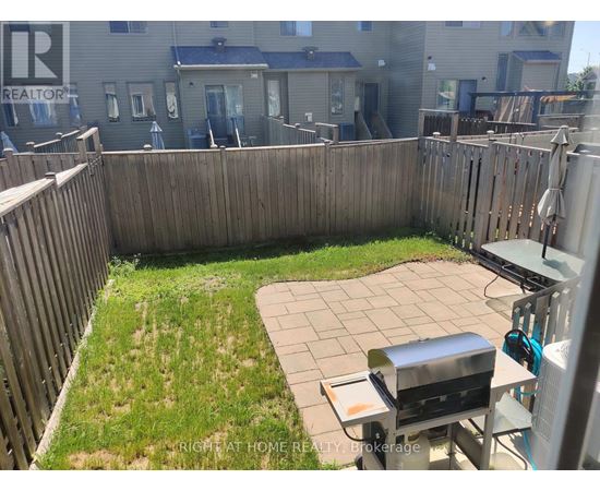 A backyard with a BBQ grill and a wooden fence.