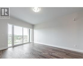 A spacious room with wooden flooring and a large window.