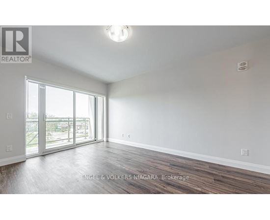 A spacious room with wooden flooring and a large window.
