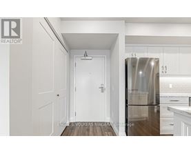 A white door is in a hallway with a brokerage logo on the bottom left.