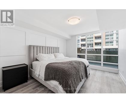 A bedroom with a large bed and a window overlooking a building.