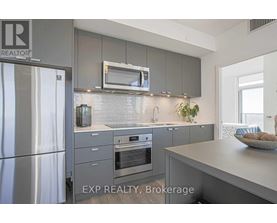 A modern kitchen with a stainless steel refrigerator and a microwave above the oven.