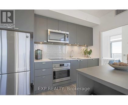 A modern kitchen with a stainless steel refrigerator and a microwave above the oven.