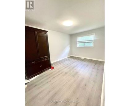 A room with a wooden floor and a window with blinds.