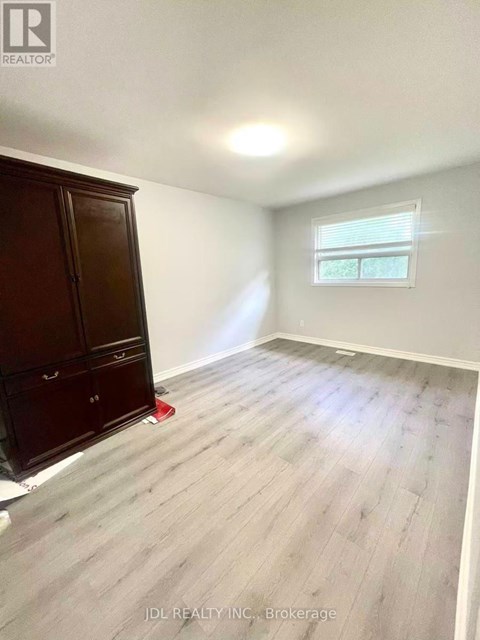 A room with a wooden floor and a window with blinds.