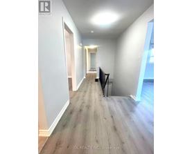 A hallway with wood flooring and white walls.