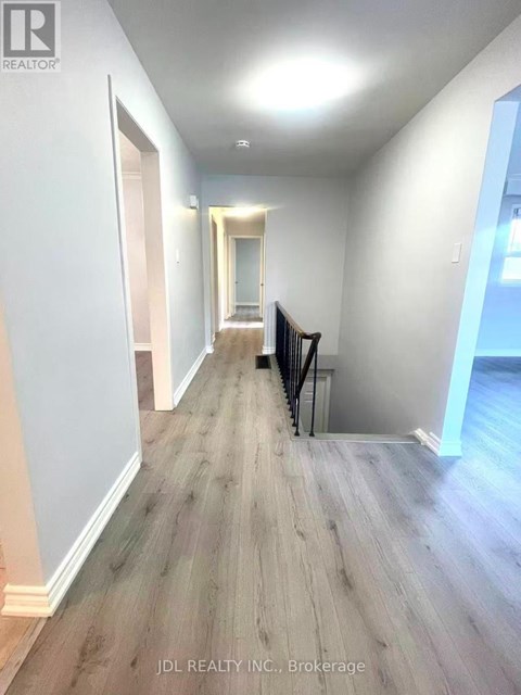A hallway with wood flooring and white walls.