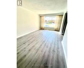 A room with wooden flooring and a window with curtains.