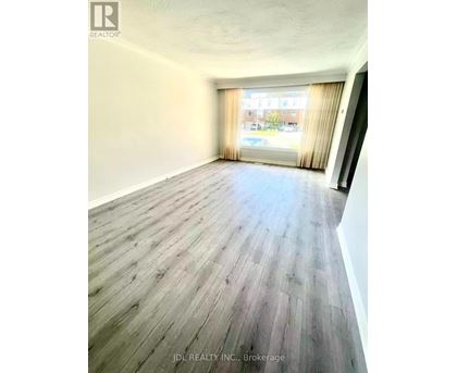A room with wooden flooring and a window with curtains.
