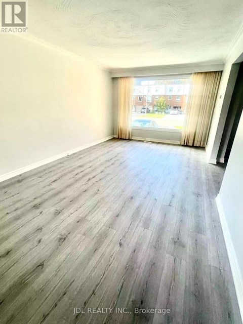 A room with wooden flooring and a window with curtains.