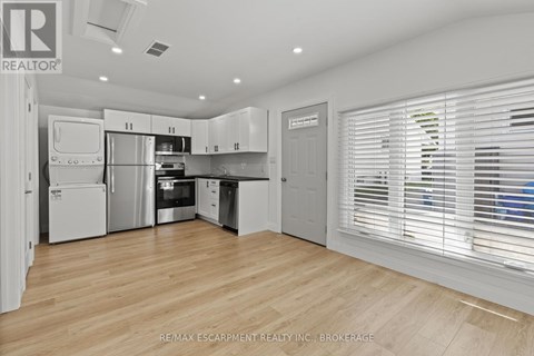 A kitchen with white cabinets and appliances in a brokerage office.