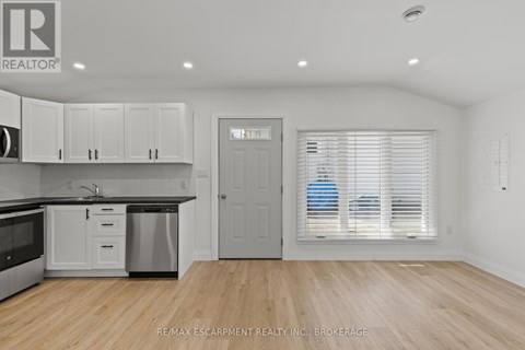 A kitchen with white cabinets and a wooden floor.