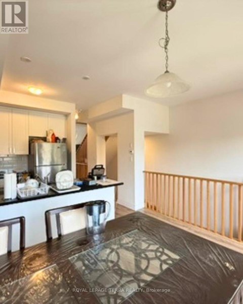 A kitchen with a table and chairs in the foreground and a balcony with a railing in the background.