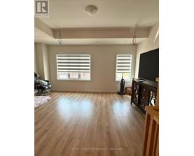 A room with wooden floors and two windows with blinds.