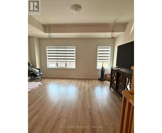 A room with wooden floors and two windows with blinds.