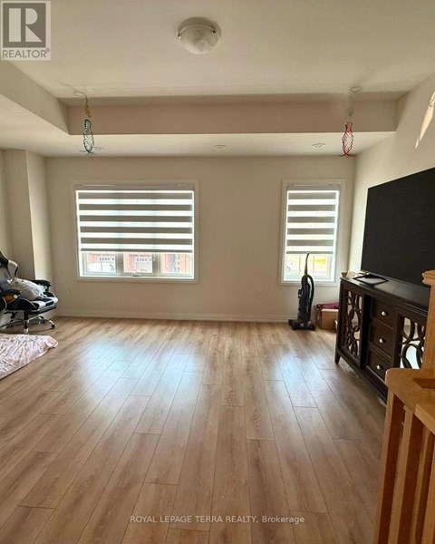 A room with wooden floors and two windows with blinds.