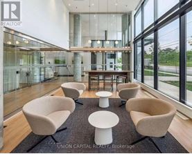 A modern waiting area with beige chairs and a glass wall.