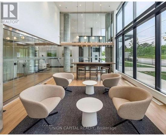 A modern waiting area with beige chairs and a glass wall.
