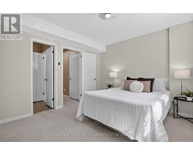 A bedroom with a large bed and a nightstand with a lamp.