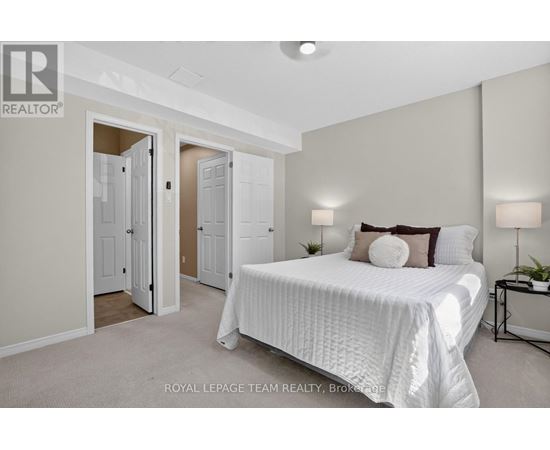 A bedroom with a large bed and a nightstand with a lamp.