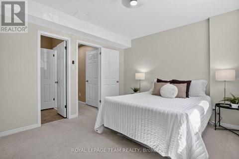 A bedroom with a large bed and a nightstand with a lamp.