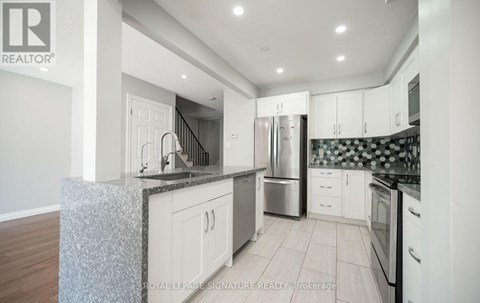 A modern kitchen with white cabinets and stainless steel appliances.