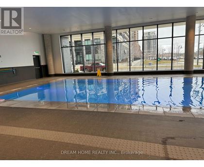 A large indoor swimming pool with a tiled floor and a glass wall overlooking the outside.