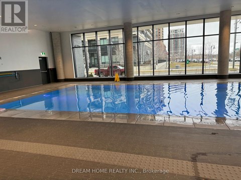 A large indoor swimming pool with a tiled floor and a glass wall overlooking the outside.