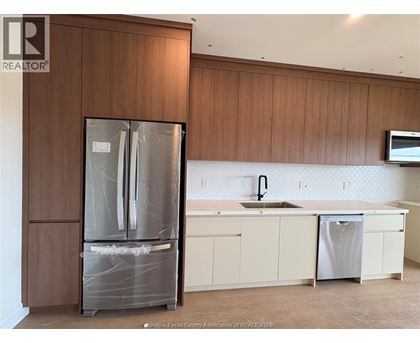 A kitchen with a refrigerator, sink, and cabinets.