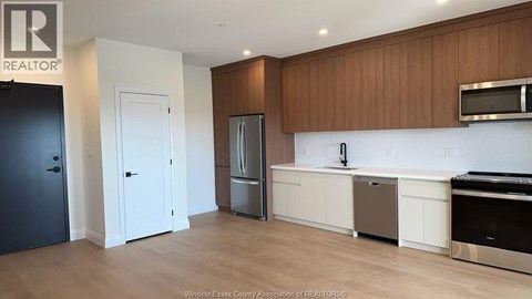 A kitchen with a refrigerator, sink, and cabinets.