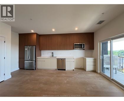 A large, empty kitchen with wooden cabinets and a refrigerator.