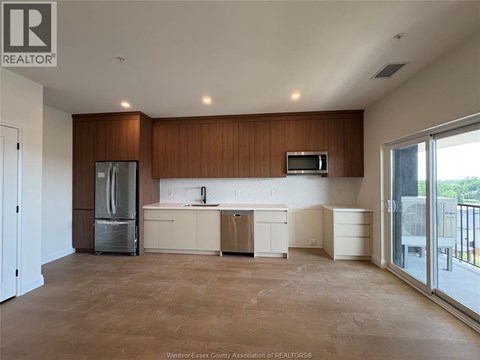 A large, empty kitchen with wooden cabinets and a refrigerator.