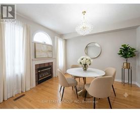 A dining room with a white table and chairs, a fireplace, and a chandelier.