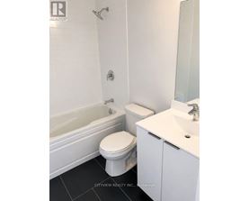A white toilet sits next to a white sink in a bathroom.