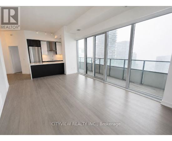 A spacious room with a bar area and large windows.