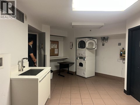 A man is standing in a kitchen with a sink and a dishwasher.