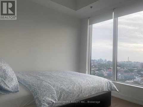 A bedroom with a bed and a window overlooking a cityscape.