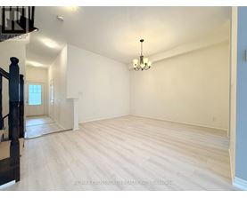 A large empty room with wooden flooring and a chandelier.