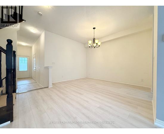 A large empty room with wooden flooring and a chandelier.