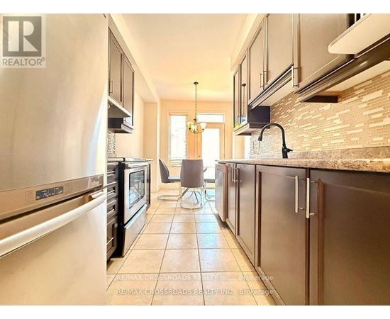 A kitchen with a tile floor and a refrigerator on the left.